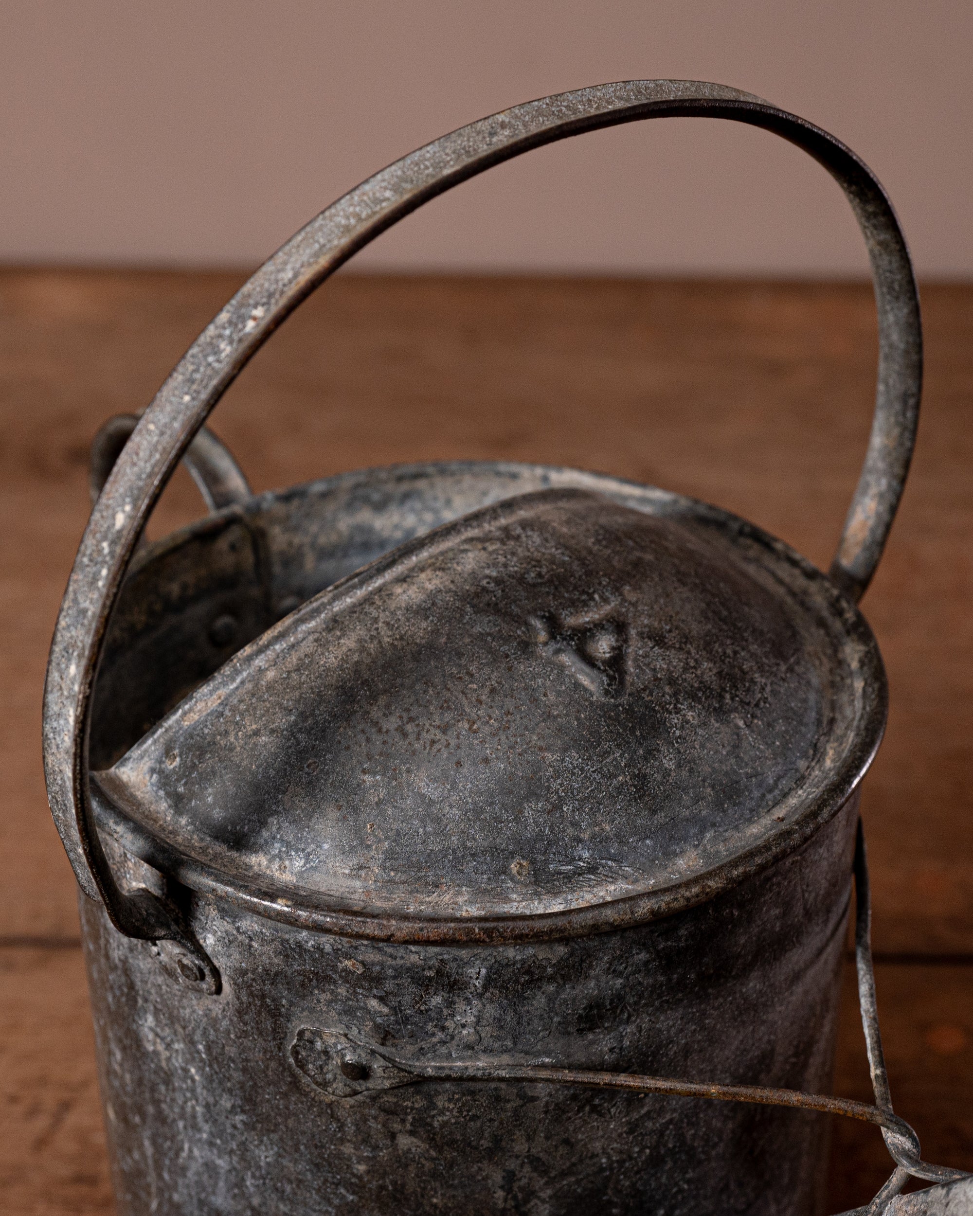 Vintage metal watering can with a handle on a wooden surface