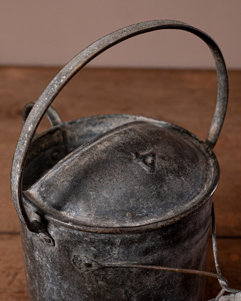 Vintage metal watering can with a handle on a wooden surface