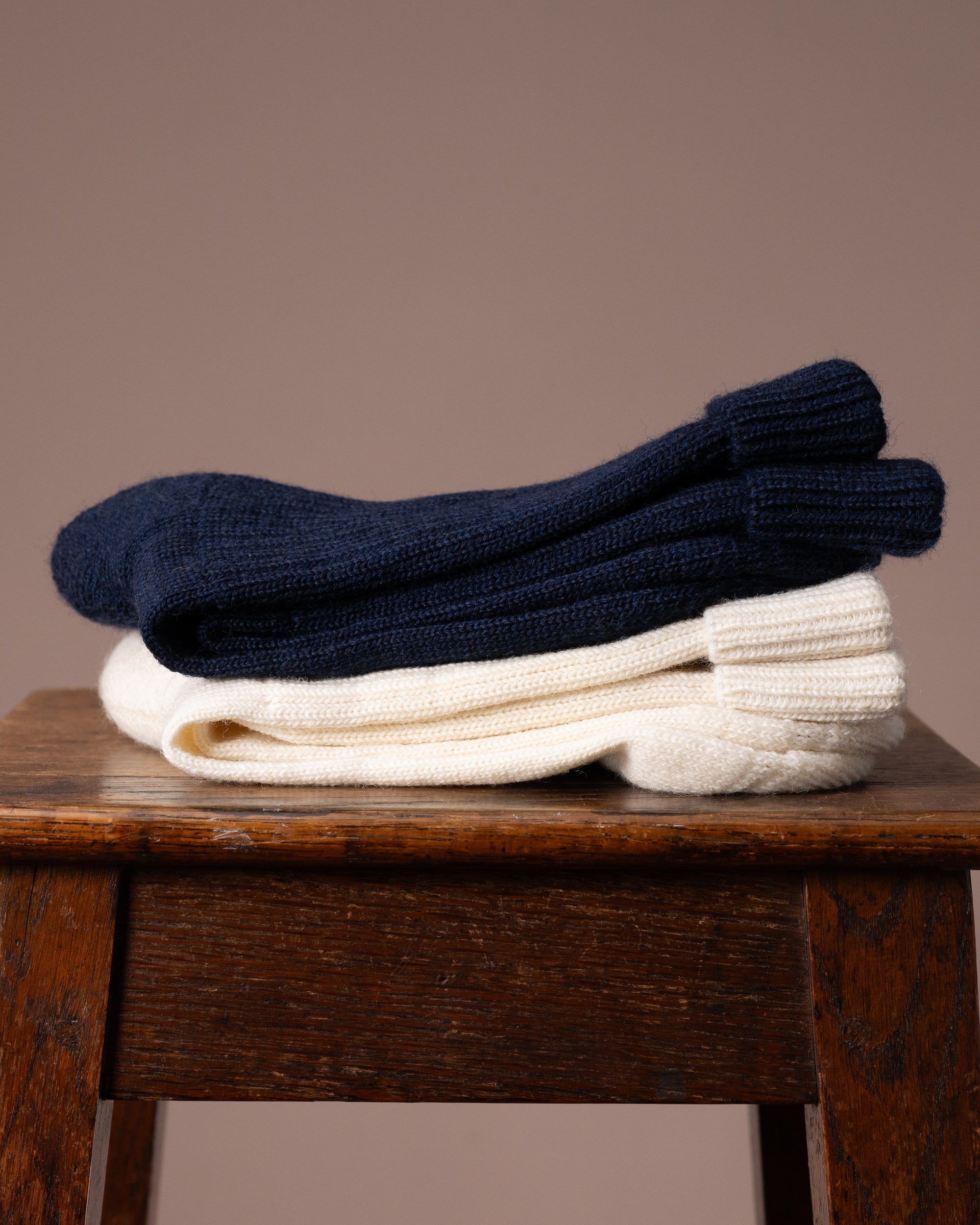 Stack of navy and white socks on a wooden stool against a brown background