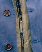 Close-up of a blue jacket with a zip and buttons.