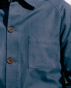 Close-up of a blue work jacket with buttons and a pocket