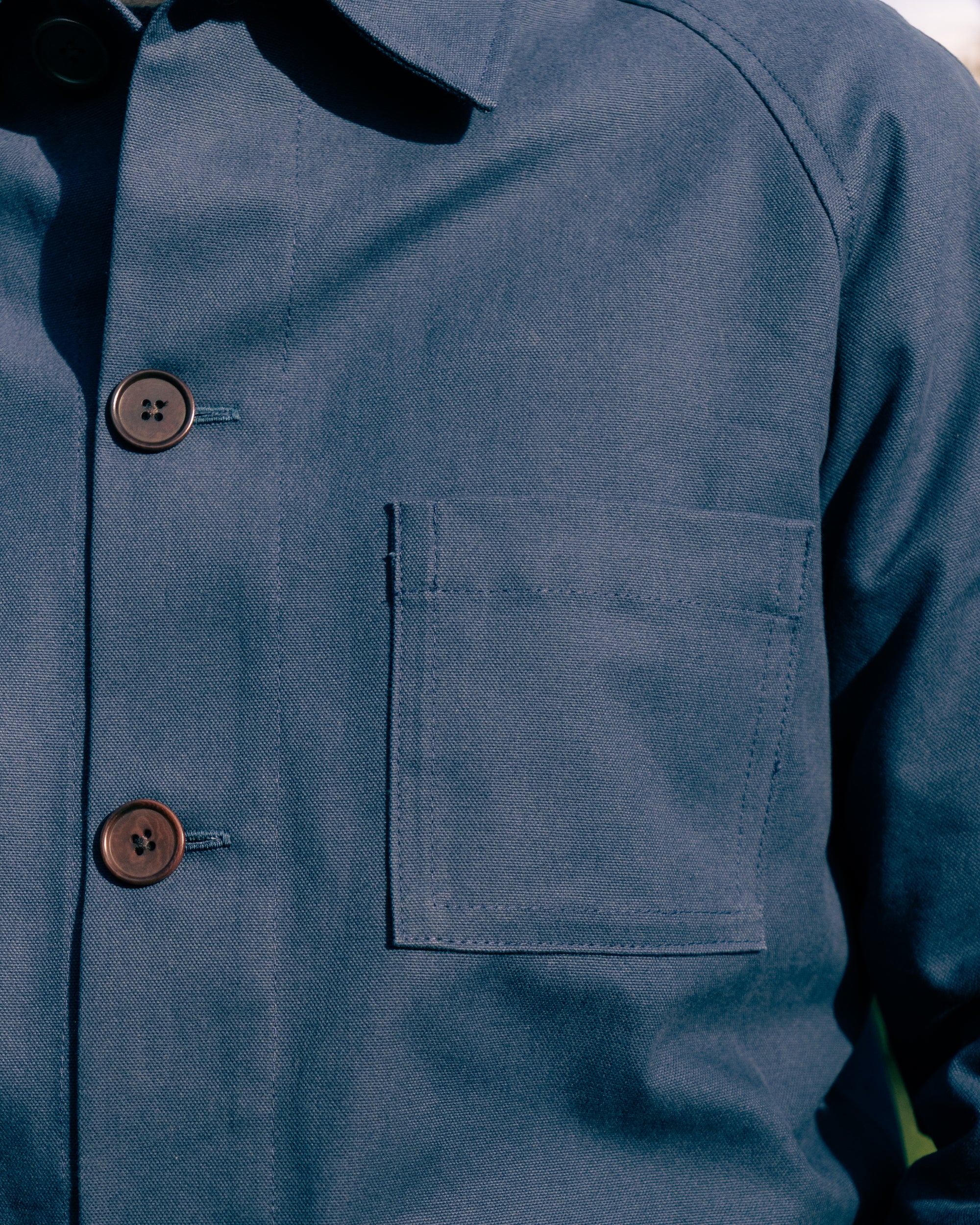 Close-up of a blue work jacket with buttons and a pocket